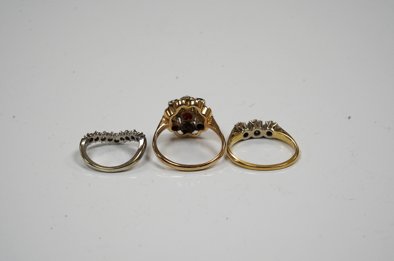 Two 18ct gold and diamond set rings including chevron shape and a 9ct gold, garnet and seed pearl set ring. Condition - fair